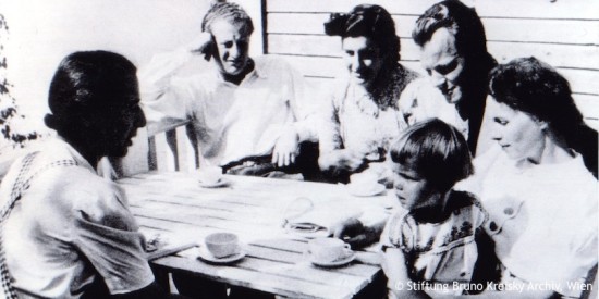 Willy Brandt sitzt mit Carlota Thorkildsen und Freunden um einen Tisch. Carlota hat Tochter Ninja auf dem Schoß. Fotografie in Schwarz-Weiß. Öffnet weitere Informationen zu dieser Ehe.