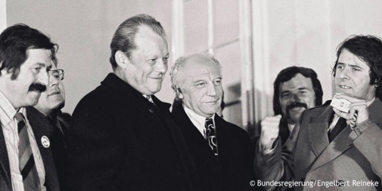 Willy Brandt steht zwischen Günter Grass und Walter Scheel. Schräg vor ihm spricht der Juso-Vorsitzende Wolfgang Roth. Fotografie in Schwarz-Weiß. Öffnet weitere Informationen zur Innen- und Gesellschaftspolitik.