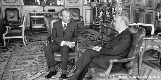 Willy Brandt sitzt neben dem französischen Staatspräsidenten Georges Pompidou in einem Zimmer des Élysée-Palasts. Fotografie in Schwarz-Weiß. Öffnet weitere Informationen Konzepten und der Politik Willy Brandts für Europa.