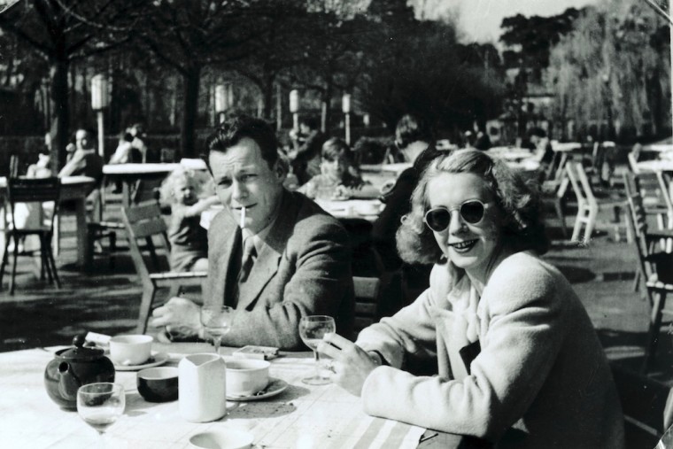 Schwarz-Weiß-Aufnahme von Willy Brandt und Rut Bergaust aus dem Jahr 1947. Die beiden sitzen im freien an einem Tisch auf dem Getränke stehen. Willy Brandt hat eine Zigarette im Mund.
