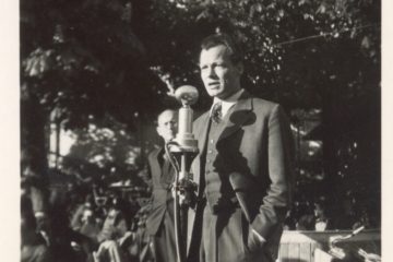 Schwarz-Weiß-Aufnahme Willy Brandts 1949, der vor einem Mikrofon steht.